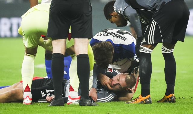 FILED - 20 December 2025, Hamburg: Hamburger's Mario Vuskovic (C) helps Eintracht Frankfurt's Rasmus Kristensen who is lying motionless on the pitch after a collision with Hamburger's Miro Muheim during the German Bundesliga soccer match between Hamburger SV and Eintracht Frankfurt at Volksparkstadion. Photo: Christian Charisius/dpa - WICHTIGER HINWEIS: Gemäß den Vorgaben der DFL Deutsche Fußball Liga bzw. des DFB Deutscher Fußball-Bund ist es untersagt, in dem Stadion und/oder vom Spiel angefertigte Fotoaufnahmen in Form von Sequenzbildern und/oder videoähnlichen Fotostrecken zu verwerten bzw. verwerten zu lassen.