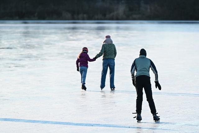 26 December 2025, Lower Saxony, Neermoor: Skaters run across the ice at the flooded surface in Neermoor lured on Boxing Day. Photo: Lars Penning/dpa