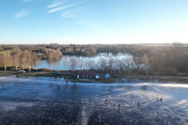 26 December 2025, Lower Saxony, Neermoor: Skaters run across the ice at the flooded surface in Neermoor lured on Boxing Day. Photo: Lars Penning/dpa