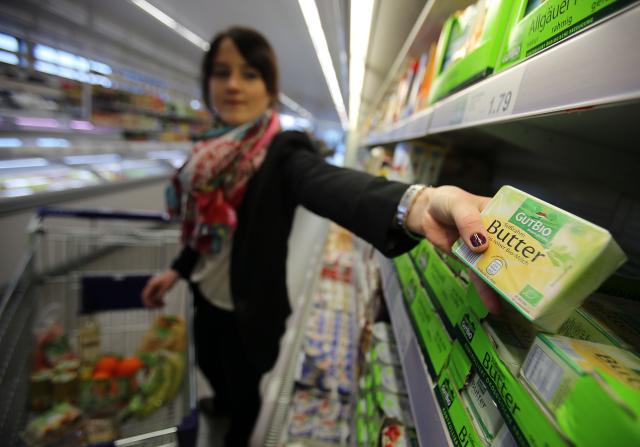 FILED - 13 March 2015, North Rhine-Westphalia, Velbert: A customer takes organic butter from a shelf at an Aldi supermarket in Velbert. Photo: picture alliance / dpa