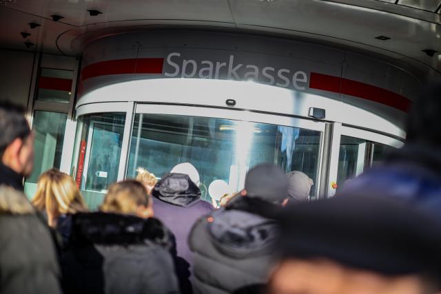 30 December 2025, North Rhine-Westphalia, Gelsenkirchen: Waiting customers stand outside the Sparkasse branch in Gelsenkirchen-Buer to get information about their safe deposit boxes after the bank's vault was broken into. Due to the situation, the branch will remain closed on Tuesday, the police announced. Photo: Christoph Reichwein/dpa