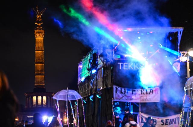31 December 2025, Berlin: Participants ride a float at the "WeAreBerlin" party on 17 June Street, with the Victory Column visible in the background. Photo: Britta Pedersen/dpa