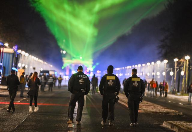 31 December 2025, Berlin: Police officers walk through the "WeAreBerlin" party on 17 June Street. Photo: Britta Pedersen/dpa