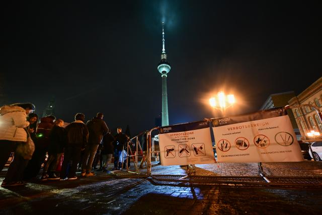 31 December 2025, Berlin: Passers-by stand at a checkpoint at the entrance to the pyrotechnics ban zone on Alexanderplatz during New Year's Eve. At the turn of the year, Berlin enforces four firecracker ban zones where fireworks, firecrackers, and the carrying of knives and weapons are prohibited. Photo: Sebastian Christoph Gollnow/dpa