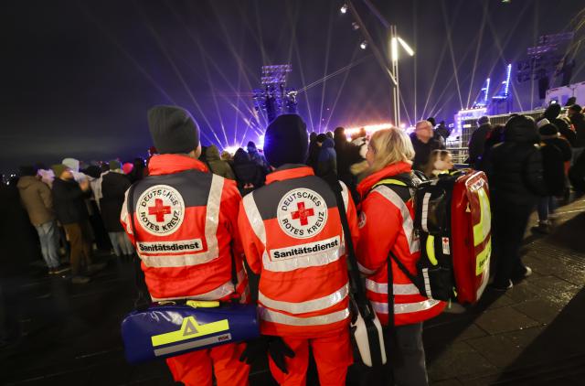 31 December 2025, Hamburg: Employees of the German Red Cross (DRK) stand in front of the floating stage of the ZDF New Year's Eve show on the Chicagikai in front of the Westfield Hamburg-Ueberseequartier in Hafencity. The ZDF New Year's Eve show is taking place in Hamburg's Hafencity for the first time. Photo: Christian Charisius/dpa