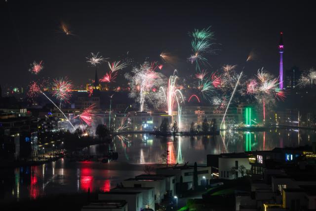 31 December 2025, North Rhine-Westphalia, Dortmund: Fireworks lights the sky over the Phoenixsee in Hoerde with the the Floriansturm (R) during the New Year's Eve celebrations. Photo: Christoph Reichwein/dpa