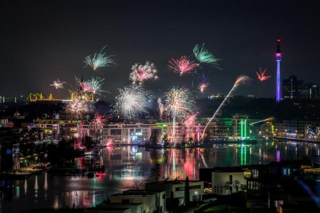 31 December 2025, North Rhine-Westphalia, Dortmund: Fireworks lights the sky over the Phoenixsee in Hoerde with the Signal-Iduna-Park (L) and the Floriansturm (R) during the New Year's Eve celebrations. Photo: Christoph Reichwein/dpa