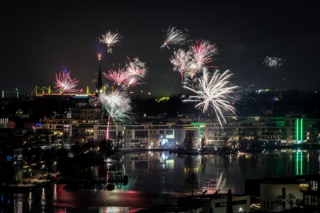 31 December 2025, North Rhine-Westphalia, Dortmund: Fireworks lights the sky over the Phoenixsee in Hoerde with the Signal-Iduna-Park (L) during the New Year's Eve celebrations. Photo: Christoph Reichwein/dpa