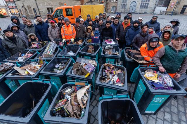 01 January 2026, Lower Saxony, Osnabrueck: Muslims pose at open garbage cans in front of Osnabrück town hall after the traditional New Year's clean-up. The Ahmadiyya community's campaign brings together 10,000 Muslims in more than 240 cities across Germany to clear the streets of New Year's garbage after praying together. Photo: Friso Gentsch/dpa