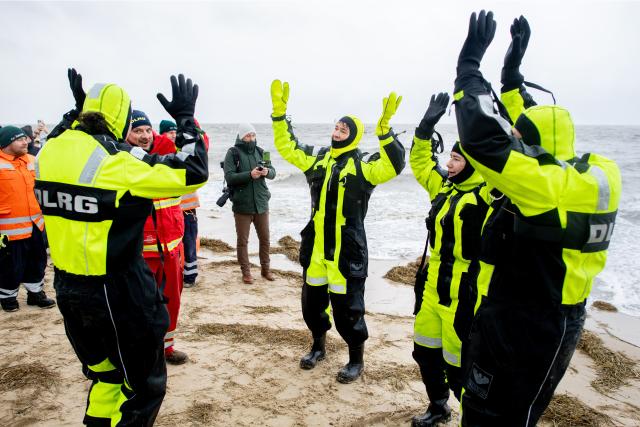 01 January 2026, Lower Saxony, Cuxhaven: Volunteer lifeguards from the DLRG dance during a New Year's swim on the beach in Duhnen. In several places on the North Sea coast of Lower Saxony, intrepid swimmers traditionally start the new year with a dip in the cold North Sea. Photo: Hauke-Christian Dittrich/dpa