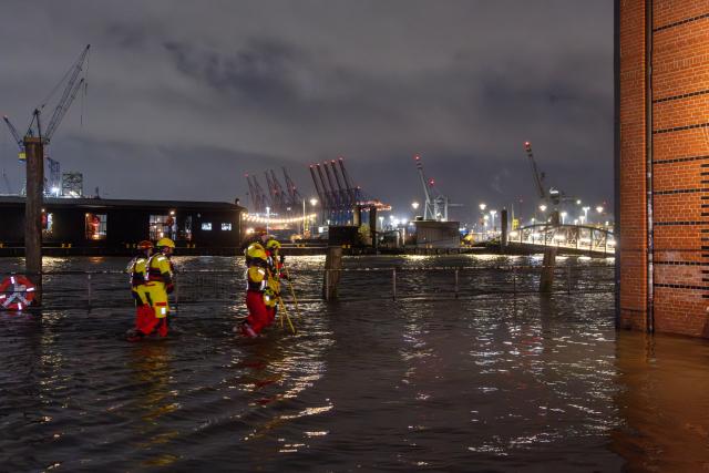 02 January 2026, Hamburg: The water of the Elbe presses down on Hamburg's fish market during high tide and a storm surge, where DLRG members are walking through the water as part of an exercise. Photo: Bodo Marks/dpa