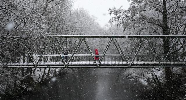 02 January 2026, Hamburg: Passers-by walk across a canal bridge during a snowstorm in Hamburg. Photo: Marcus Brandt/dpa