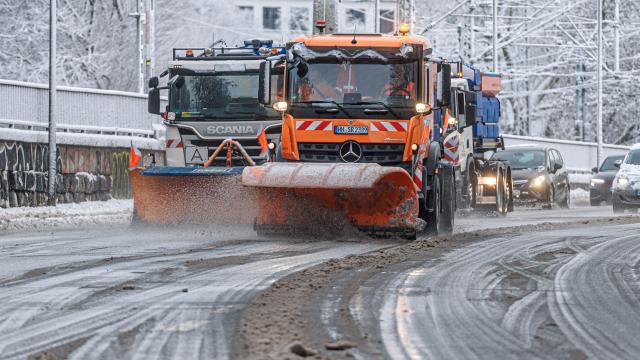 03 January 2026, Hamburg: Winter road clearance vehicles clear snow and grit the roadway on the Lombardsbruecke bridge as a cold polar air mass brings wintry weather to Hamburg and Schleswig-Holstein, with snow, frost, icy conditions and at times gale-force winds. Photo: Markus Scholz/dpa