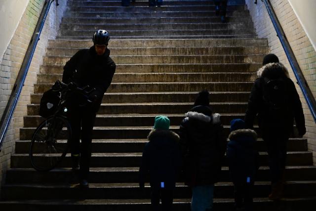 03 January 2026, Berlin: A man carries his bicycle down a flight of stairs during a power outage at the Mexikoplatz S-Bahn station in southwest Berlin. Trains are no longer stopping at the station because the platform is unlit. Following a cable bridge fire, around 50,000 households and 2,000 businesses in southwest Berlin lost power. Photo: Sebastian Christoph Gollnow/dpa