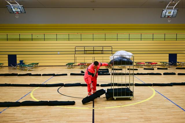 03 January 2026, Berlin: A volunteer from the German Red Cross (DRK) unloads camp beds in an emergency shelter during a power outage in southwest Berlin. After a cable bridge caught fire, 50,000 households and 2,000 businesses in south-west Berlin lost power. Photo: Sebastian Christoph Gollnow/dpa