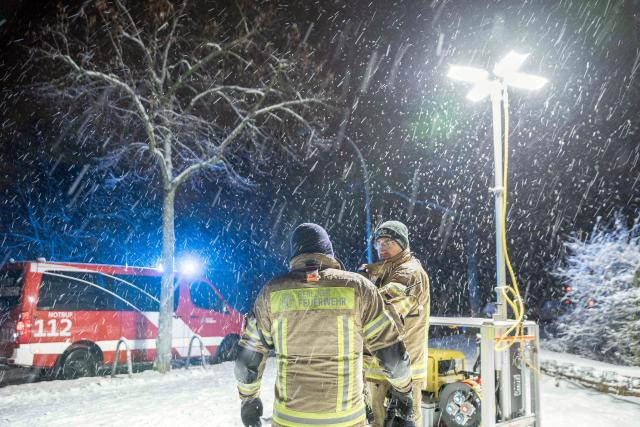 03 January 2026, Berlin: Emergency services from the Berlin fire department stand in front of a generator light pole at a civil protection contract point in front of the Carl Schuhmann sports facility in the Lichterfelde district during a power outage. After a cable bridge caught fire, 50,000 households and 2,000 businesses in south-west Berlin lost power. Photo: Carsten Koall/dpa