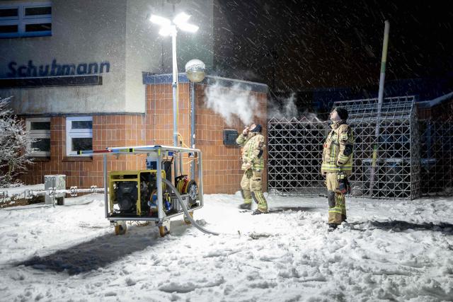 03 January 2026, Berlin: Emergency services from the Berlin fire department stand in front of a generator light pole at a civil protection contract point in front of the Carl Schuhmann sports facility in the Lichterfelde district during a power outage. After a cable bridge caught fire, 50,000 households and 2,000 businesses in south-west Berlin lost power. Photo: Carsten Koall/dpa