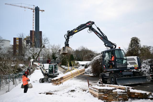 04 January 2026, Berlin: An excavator picks up beams for the construction site in front of the burnt-out cable bridge during a power cut in south-west Berlin. Tens of thousands in the area are without electricity after a politically motivated arson attack on Saturday morning damaged key lines on the bridge over the Teltow Canal to Lichterfelde power station. Photo: Sebastian Christoph Gollnow/dpa
