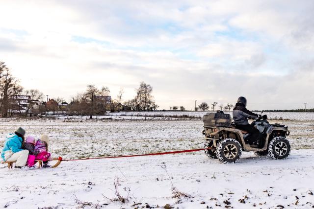 04 January 2026, Brandenburg, Leuthen: A man uses a quad bike as a tractor for a sledge with children on it. Photo: Frank Hammerschmidt/dpa
