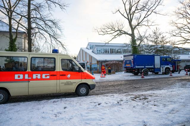 05 January 2026, Berlin: Vehicles from the Deutsche Lebens-Rettungs-Gesellschat DLRG and the THW technical relief organization are parked in front of a gymnasium at Dreilinden-Gymnasium. Tens of thousands of people in the southwest of the capital have no electricity. Photo: Christophe Gateau/dpa
