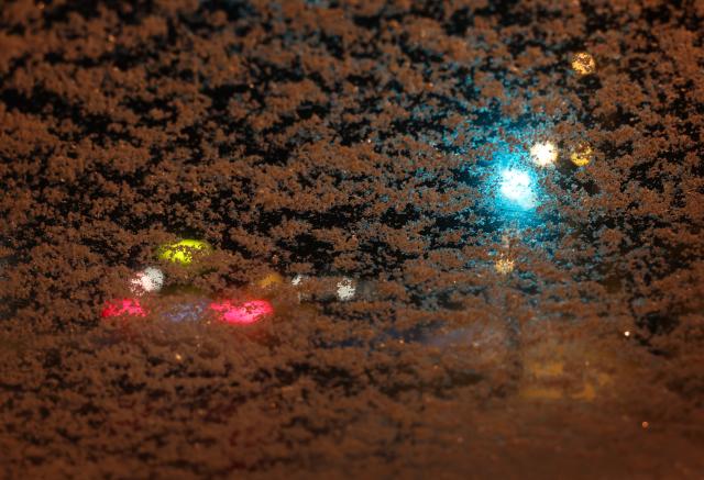 06 January 2026, Bavaria, Wuerzburg: The lights of a taxi and a traffic signal glow behind a snow-covered car windshield in the early morning. Photo: Karl-Josef Hildenbrand/dpa