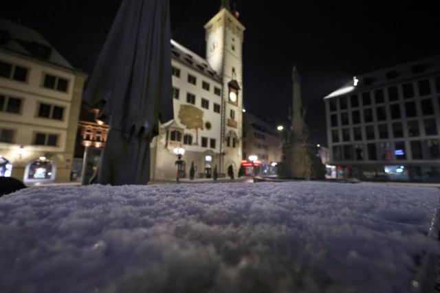 06 January 2026, Bavaria, Wuerzburg: The town hall rises behind a snow-covered table in the early morning. Photo: Karl-Josef Hildenbrand/dpa