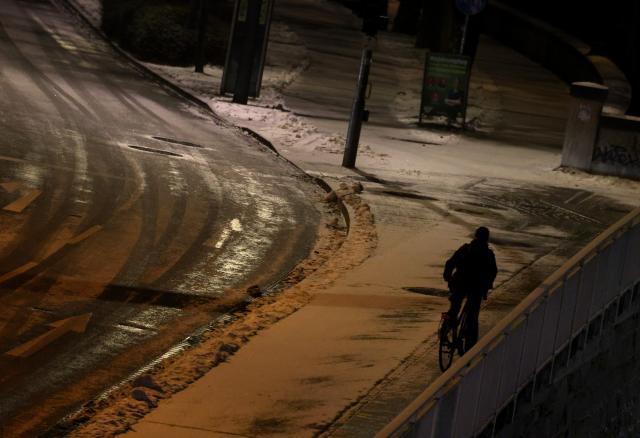 06 January 2026, Bavaria, Wuerzburg: A cyclist pedals along a snow-covered bike path in the early morning. Photo: Karl-Josef Hildenbrand/dpa