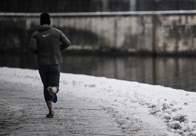 06 January 2026, Berlin: A man jogs along the snow-covered banks of the Spree in Berlin. Photo: Britta Pedersen/dpa
