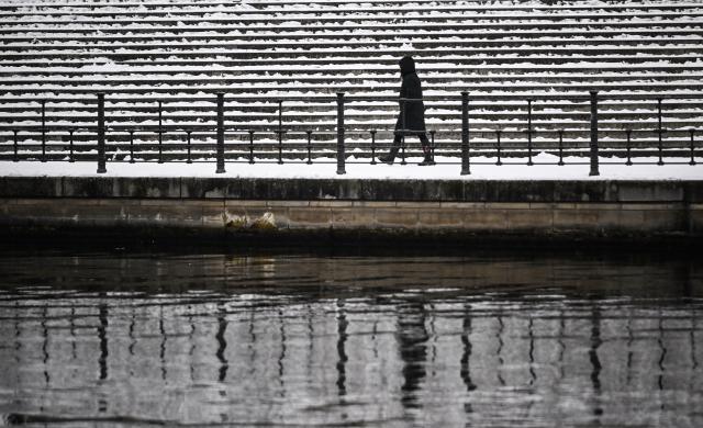 06 January 2026, Berlin: A person walks along the snow-covered banks of the Spree. Photo: Britta Pedersen/dpa