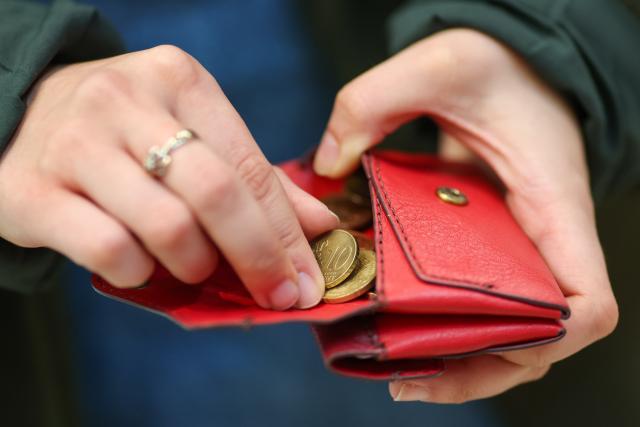 FILED - 12 March 2025, Saxony, Leipzig: A woman counts places coins inside a red wallet. German consumer prices rose by 2.2% year-on-year in 2025, with inflation remaining on the same level recorded in 2024, official estimates showed on Tuesday, as pressure on consumers continued to ease. Photo: Jan Woitas/dpa