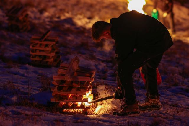 06 January 2026, Bavaria, Pottenstein: A fire-stoker lights one of the numerous mountain fires on the rocks at the end of the "Eternal Adoration" festival. Photo: Daniel Löb/dpa