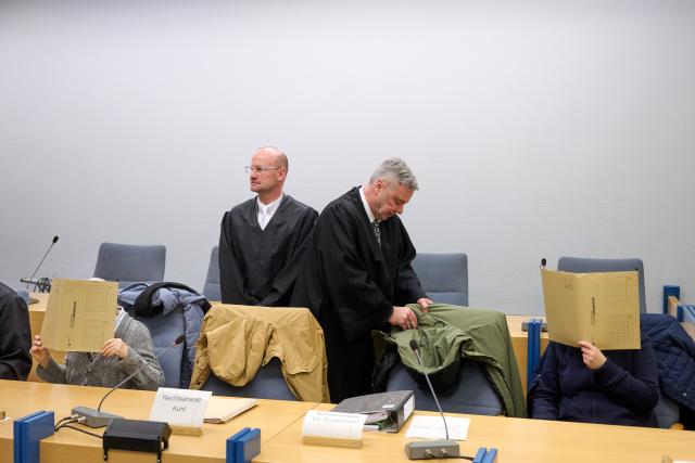07 January 2026, North Rhine-Westphalia, Siegen: An accused grandmother (L) and an accused mother hide their faces behind files in the courtroom. The lawyers Stephan Kuhl (2-L) and Peter Endemann (2-R). For seven years, a woman is said to have kept her daughter in her grandparents' house in Attendorn in North Rhine-Westphalia - hidden and completely isolated from the outside world. Photo: Bernd Thissen/dpa