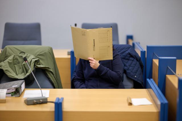 07 January 2026, North Rhine-Westphalia, Siegen: An accused mother hides her face behind a file in the courtroom. For seven years, from the time she was a baby, the woman is said to have kept her daughter in her grandparents' house in Attendorn in North Rhine-Westphalia - hidden and completely isolated from the outside world. Photo: Bernd Thissen/dpa