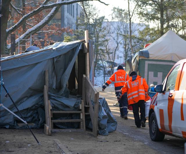 07 January 2026, Berlin: Employees of HAN Netzbau GmbH carry material behind a tent on the site of the substation on Argentinische Allee. After days of widespread power cuts in the south-west of Berlin, the power supply to the affected area has been restored. Photo: Soeren Stache/dpa