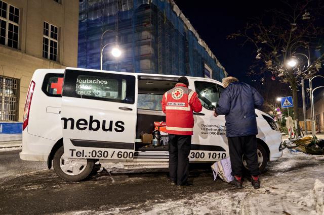 07 January 2026, Berlin: DRK Warm Bus volunteer Sebastian Ulm offers a hot cup of tea to a person in need in front of Berlin's Zoologischer Garten S-Bahn station amid freezing temperatures. The DRK Warm Bus volunteers go out every evening to help the city's homeless, visiting known sleeping areas and distributing tea, sleeping bags, mats, and other warming supplies. Temperatures in Berlin are expected to remain below freezing on Thursday. Photo: Michael Ukas/dpa