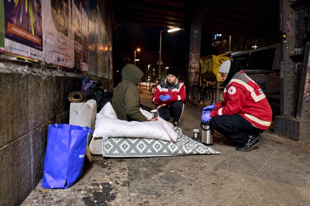 07 January 2026, Berlin: DRK Warm Bus volunteers Lisa Wiedemann and Sebastian Ulm meet a person in need from Ukraine at Berlin's Bellevue S-Bahn station. The volunteers visit known sleeping areas every evening to provide the homeless with tea, sleeping bags, mats, and other warming items as temperatures remain below freezing. Photo: Michael Ukas/dpa