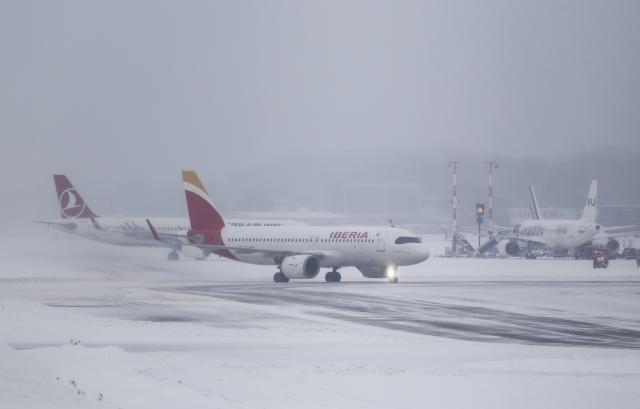 08 January 2026, Hamburg: Two planes are taxiing on the snow-covered runway at Hamburg Airport. Photo: Christian Charisius/dpa