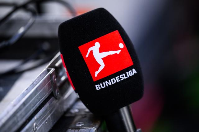 FILED - 14 December 2025, Baden-Württemberg, Freiburg im Breisgau: The German Bundesliga logo can be seen on a microphone. The German Football League (DFL) announced on Thursday that all Bundesliga soccer matches will take place as scheduled this weekend despite the winter weather. Photo: Tom Weller/dpa - IMPORTANT NOTE: In accordance with the regulations of the DFL German Football League and the DFB German Football Association, it is prohibited to utilize or have utilized photographs taken in the stadium and/or of the match in the form of sequential images and/or video-like photo series.