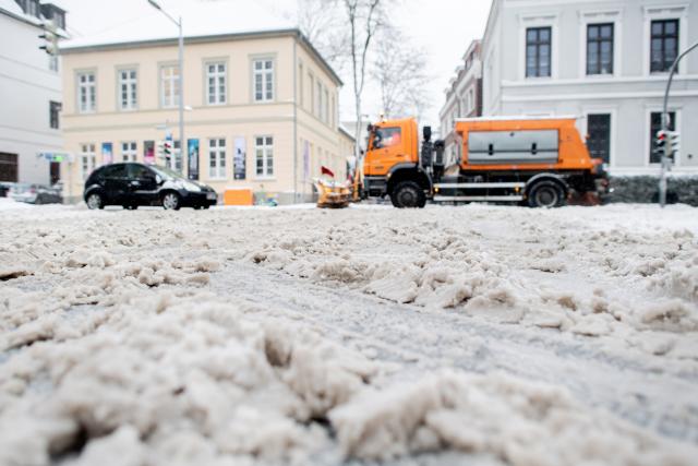 09 January 2026, Lower Saxony, Oldenburg: Snow covers a street in the city center while a winter road clearance vehicle is on its way. Photo: Hauke-Christian Dittrich/dpa