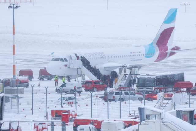 09 January 2026, Hamburg: Passengers board a Eurowings aircraft in snowy conditions and icy winds. Photo: Bodo Marks/dpa