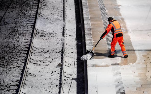 10 January 2026, Hamburg: A man clears snow from a platform at the main station in the morning. In the north, there are still restrictions on rail traffic after storm Elli. Photo: Daniel Bockwoldt/dpa