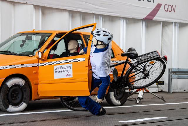 FILED - 14 July 2020, North Rhine-Westphalia, Münster: In a crash test conducted by the insurers' accident researchers, a crash test dummy on a bicycle crashes into an open door of a parked car - a so-called dooring accident. Photo: Guido Kirchner/dpa