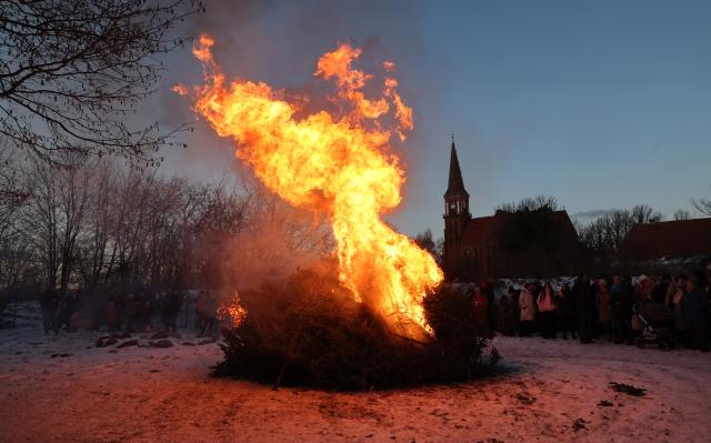 10 January 2026, Mecklenburg-Western Pomerania, Wustrow: Visitors enjoy warming themselves up at the traditional Christmas tree burning in the Bodden harbor of the Baltic Sea resort. Photo: Bernd Wüstneck/dpa