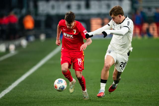 11 January 2026, North Rhine-Westphalia, Moenchengladbach: Augsburg's Robin Fellhauer (L) and Moenchengladbach's Luca Netz battle for the ball during the German Bundesliga soccer match between Borussia Moenchengladbach and FC Augsburg at the Borussia-Park Stadium. Photo: Marius Becker/dpa - IMPORTANT NOTICE: DFL and DFB regulations prohibit any use of photographs as image sequences and/or quasi-video.