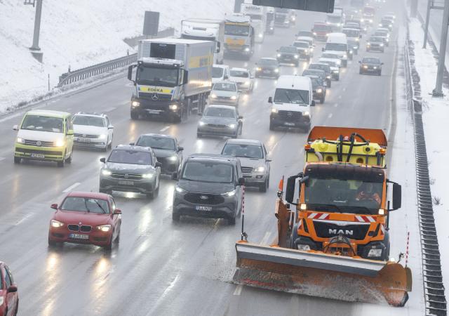 12 January 2026, Bavaria, Munich: A snowplow, cars, and trucks drive on the A9 highway in northern Munich during snowfall. Photo: Peter Kneffel/dpa