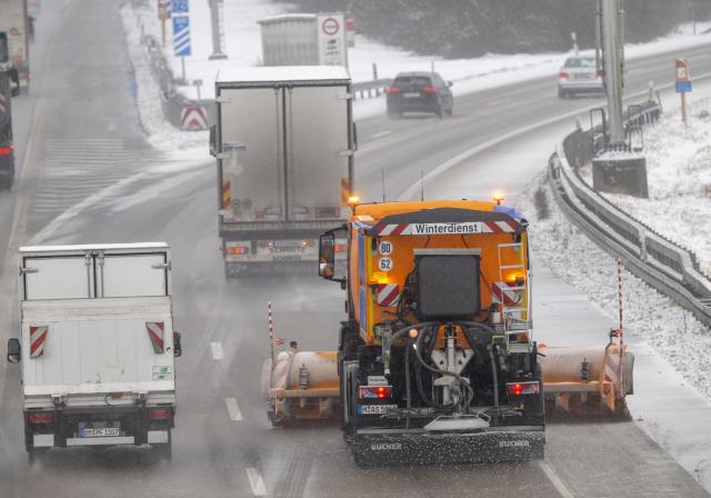 12 January 2026, Bavaria, Munich: A snowplow, cars, and trucks drive on the A9 highway in northern Munich during snowfall. Photo: Peter Kneffel/dpa