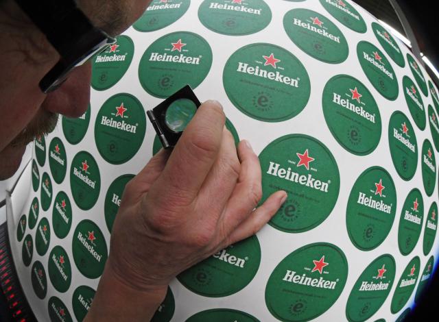 FILED - 14 February 2019, Baden-Wuerttemberg, Weisenbach: A quality assurance inspection is conducted on a printed sheet of coasters featuring the logos of the Dutch beer company Heineken. Photo: Uli Deck/dpa