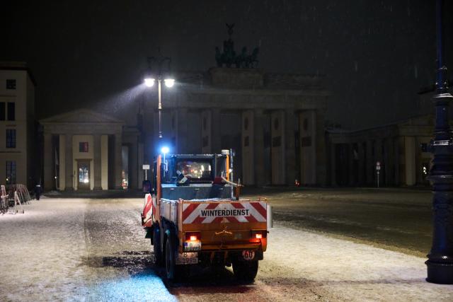 13 January 2026, Berlin: A BSR gritting vehicle grits the Brandenburg Gate while it is raining and wet patches are forming on the ground. Photo: Annette Riedl/dpa