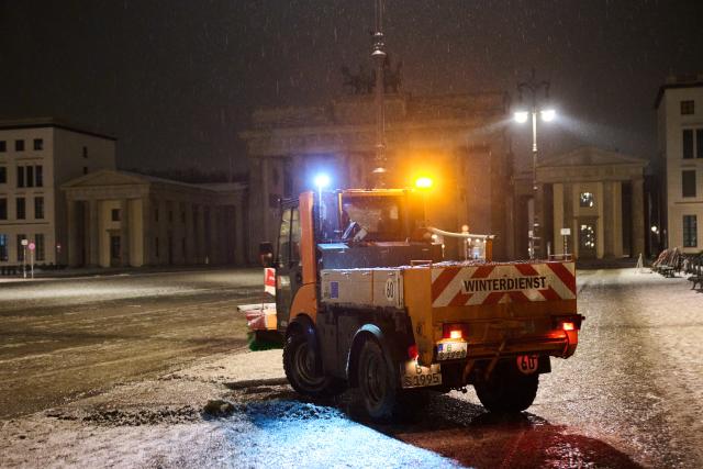 13 January 2026, Berlin: A BSR gritting vehicle grits the Brandenburg Gate while it rains and wet patches form on the ground. Photo: Annette Riedl/dpa