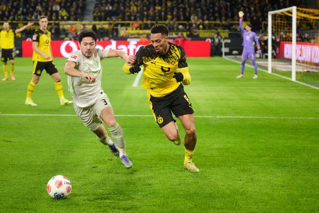 13 January 2026, North Rhine-Westphalia, Dortmund: Borussia Dortmund's Felix Nmecha (R) and Werder Bremen's Yukinari Sugawara battle for the ball during the German Bundesliga soccer match between Borussia Dortmund and Werder Bremen at Signal Iduna Park. Photo: Bernd Thissen/dpa - IMPORTANT NOTE: In accordance with the regulations of the DFL German Football League and the DFB German Football Association, it is prohibited to utilize or have utilized photographs taken in the stadium and/or of the match in the form of sequential images and/or video-like photo series.